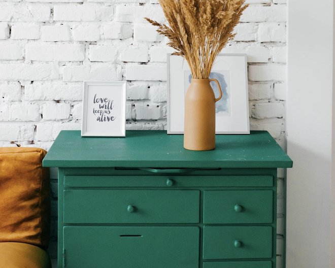 Green dresser with decorative items and dried plants