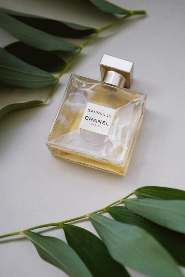 Gabrielle Chanel perfume bottle surrounded by green leaves